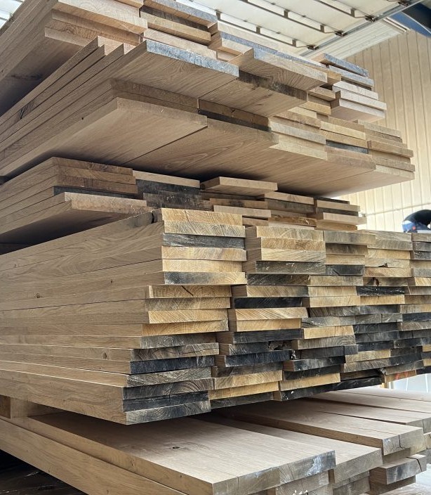 Voorraad massief eikenhouten planken in een houtzagerij. Natuurlijk gedroogd eikenhout voor de productie van vloeren en meubels.